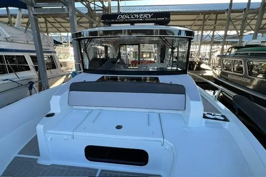Slide: The Image of 2024 Jeanneau NC 895 Sport boat docked at marina, showcasing sleek design and spacious deck. - 20