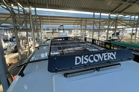 Slide: The Image of 2024 Jeanneau NC 895 Sport boat with dual outboard engines docked under a canopy. - 23