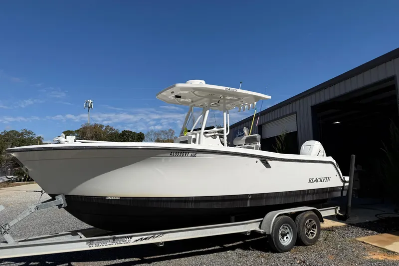 Slide: The Image of 2019 Blackfin 242 CC boat on trailer, parked outdoors under clear blue sky. - 37