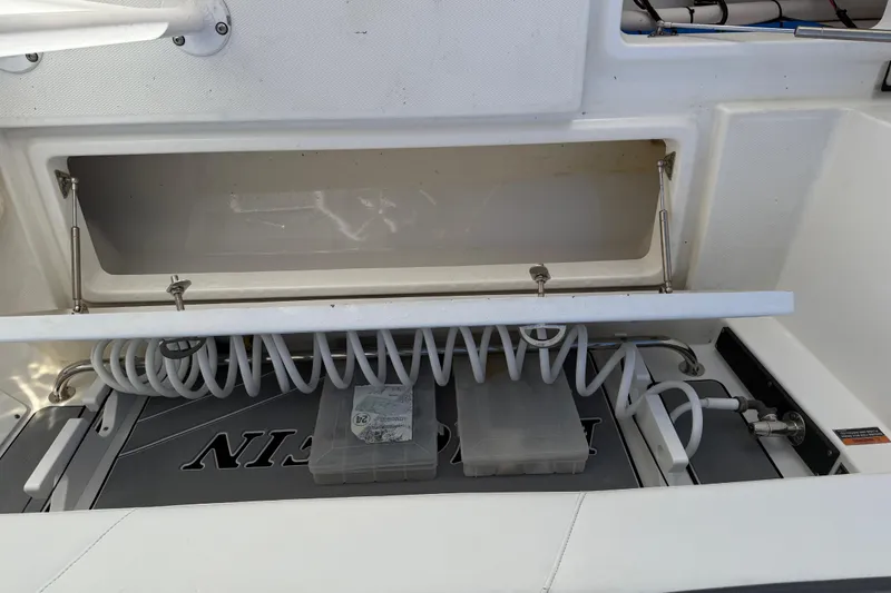 Slide: The Image of 2019 Blackfin 242 CC boat storage compartment with coiled hose and tackle boxes. - 41