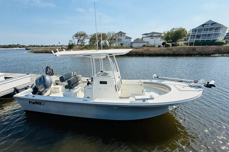 Slide: The Image of 2018 Parker 23SE Center Console boat docked on a calm river with houses in the background. - 10