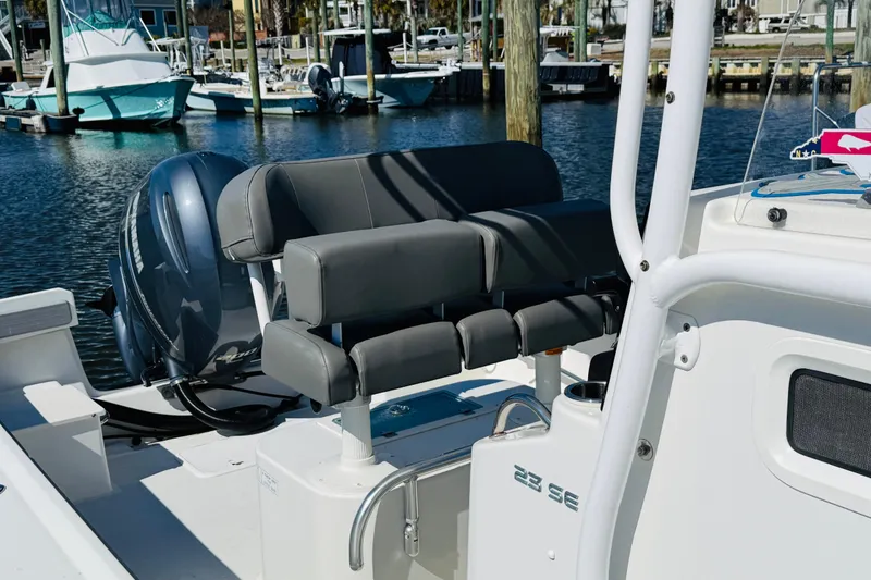 Slide: The Image of 2018 Parker 23SE Center Console boat with cushioned seating and outboard motor in marina. - 6