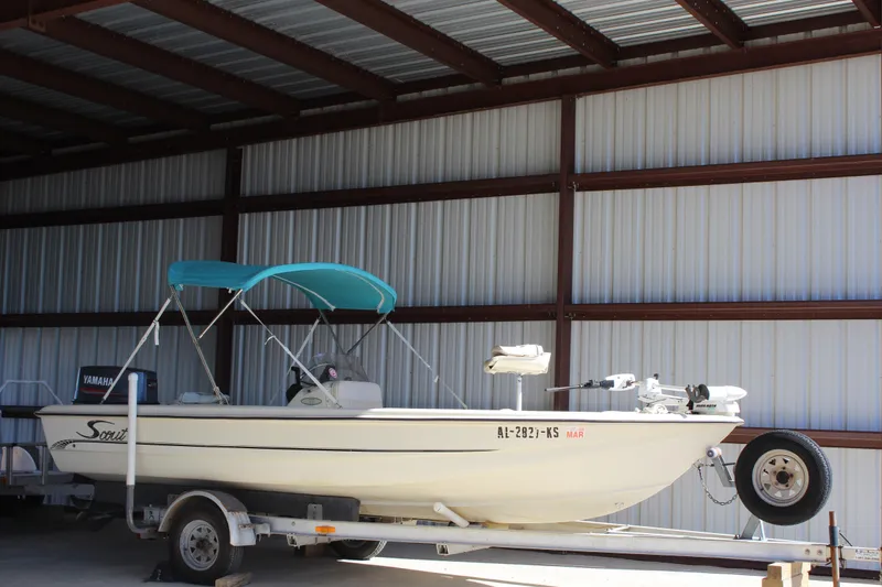 Slide: The Image of 1999 Scout 177 Sportfish boat with blue canopy on trailer in storage. - 4