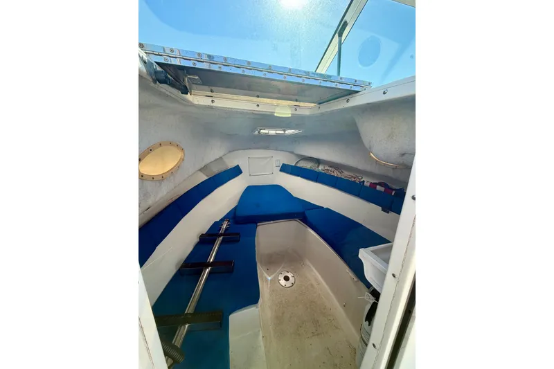 Slide: The Image of 2019 Aquasport 215 Explorer cabin interior with blue seating and open hatch. - 14