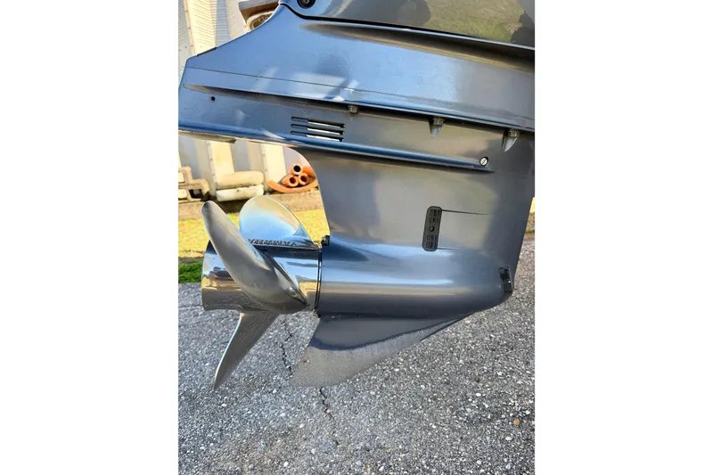 Slide: The Image of 2019 Aquasport 215 Explorer boat motor with shiny propeller on pavement. - 17
