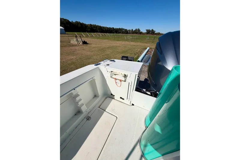 Slide: The Image of 2019 Aquasport 215 Explorer boat interior with engine, set against a grassy landscape. - 8