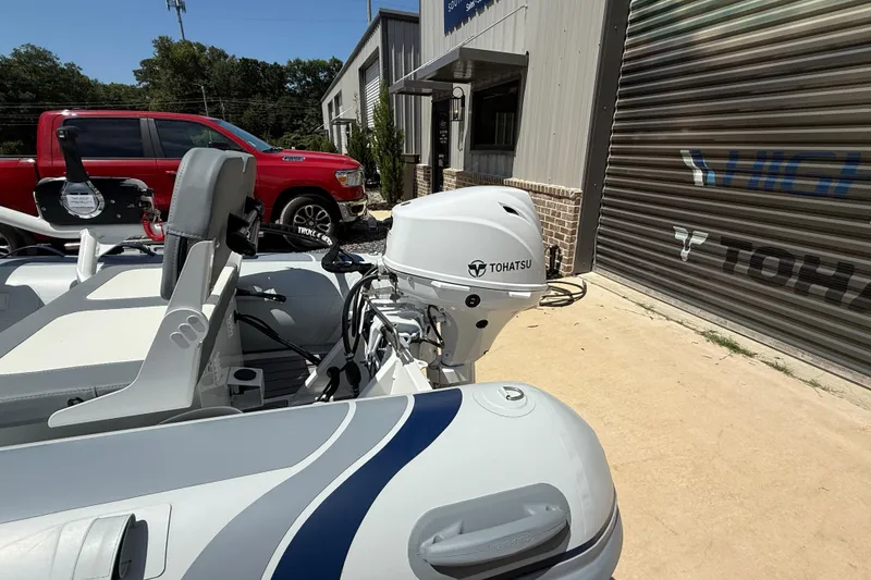 Slide: The Image of 2026 Highfield Classic 310 FCT boat with Tohatsu engine, parked near a building. - 5