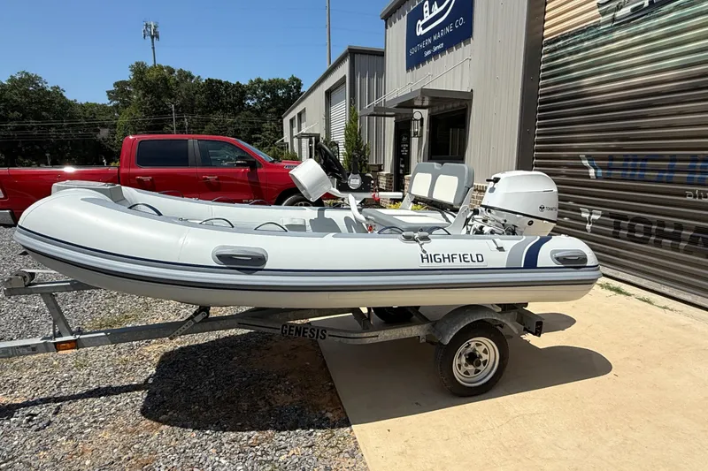 Slide: The Image of 2026 Highfield Classic 340 FCT inflatable boat on trailer outside marine store. - 5
