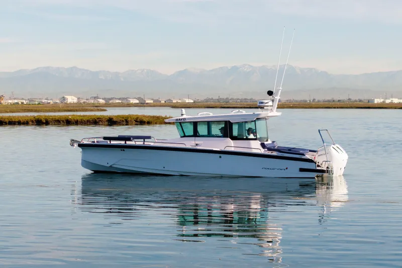The Image of 2024 Axopar 29 XC Cross Cabin boat on calm water with mountain backdrop. - 0