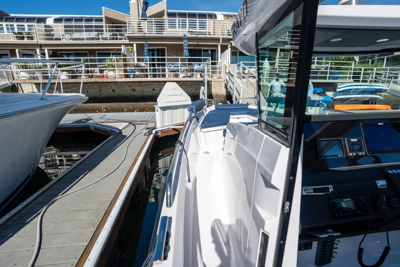 Slide: The Image of 2024 Axopar 29 XC Cross Cabin docked at a marina with modern architecture. - 25