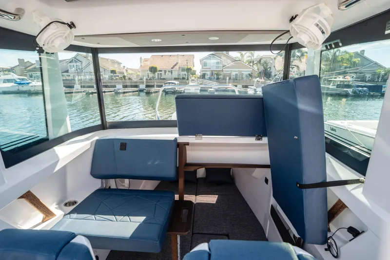Slide: The Image of 2024 Axopar 29 XC Cross Cabin interior with blue seating and waterfront view. - 31