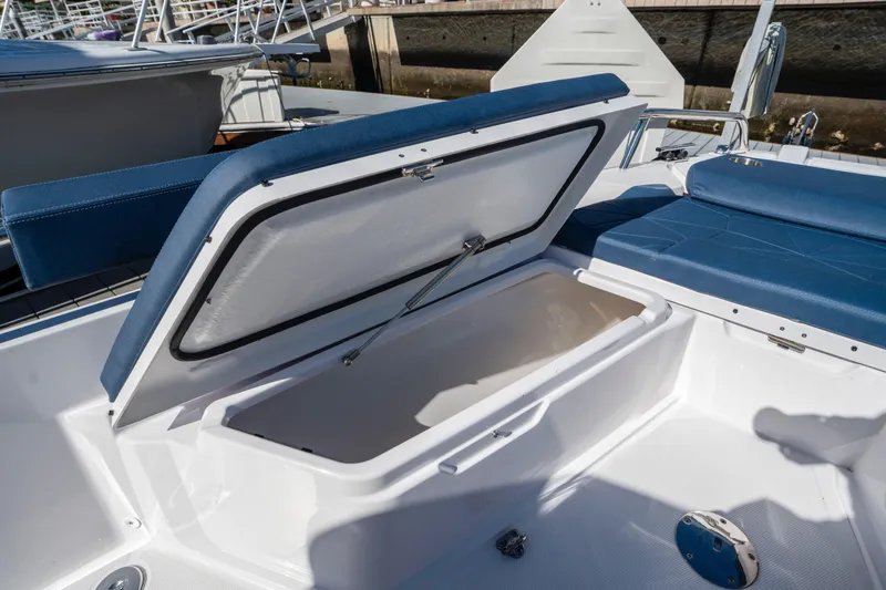 Slide: The Image of 2024 Axopar 29 XC Cross Cabin boat with open storage compartment and blue seating. - 38