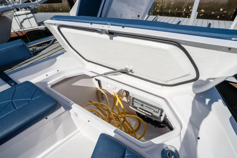 Slide: The Image of 2024 Axopar 29 XC Cross Cabin storage compartment with yellow cables and control panel. - 42