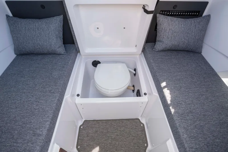 Slide: The Image of 2024 Axopar 29 XC Cross Cabin interior with hidden toilet and gray cushions. - 47