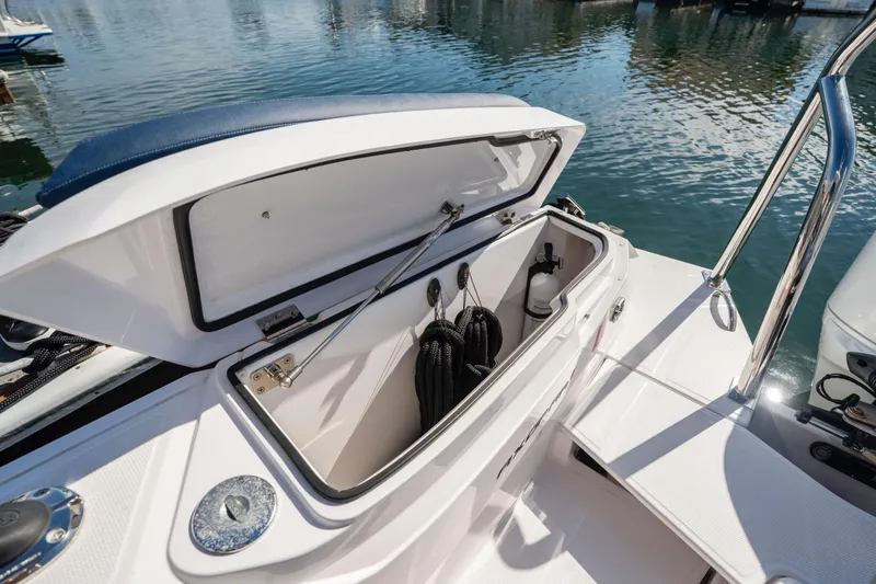 Slide: The Image of Open storage compartment on 2024 Axopar 29 XC Cross Cabin boat, docked by the water. - 49