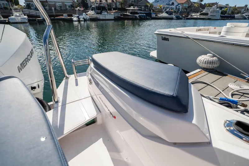 Slide: The Image of 2024 Axopar 29 XC Cross Cabin boat docked in a marina, featuring a cushioned seat. - 50