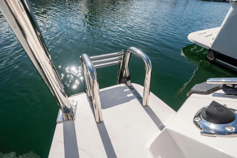Slide: The Image of 2024 Axopar 29 XC Cross Cabin boat ladder and deck by the water. - 52