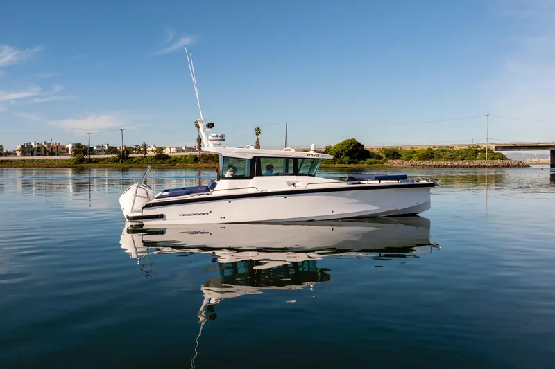 Slide: The Image of 2024 Axopar 29 XC Cross Cabin boat on calm water under clear blue sky. - 6