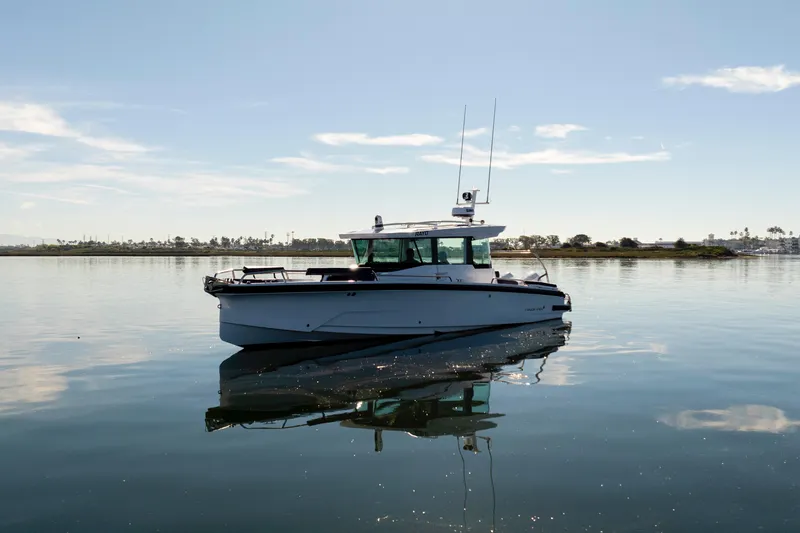 Slide: The Image of 2024 Axopar 29 XC Cross Cabin boat on calm water under clear sky. - 8