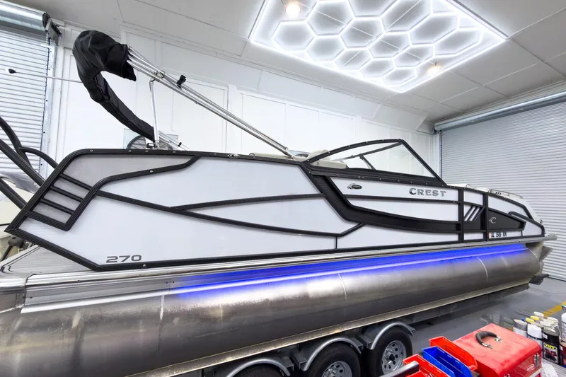 Slide: The Image of 2020 Crest Continental 270 NX-L Twin pontoon boat in a modern garage setting. - 8