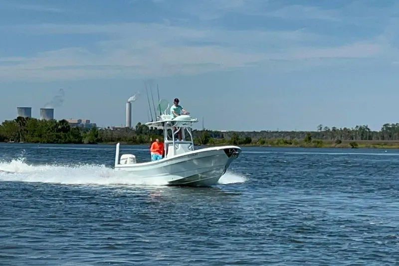 Slide: The Image of 2014 Andros Tarpon 26 boat cruising on a lake with industrial background. - 9