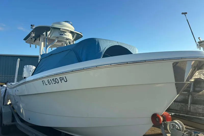 Slide: The Image of 2014 Andros Tarpon 26 boat on trailer, blue cover, clear sky background. - 7