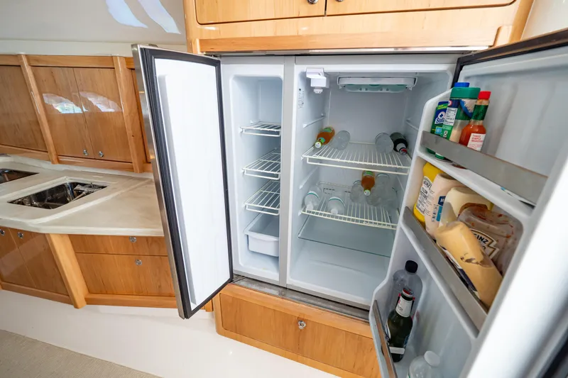 Slide: The Image of Open fridge in 2018 Intrepid 475 Sport Yacht kitchen, stocked with beverages and condiments. - 138