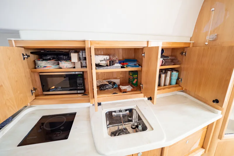 Slide: The Image of 2018 Intrepid 475 Sport Yacht kitchen with microwave, sink, and wooden cabinets. - 140