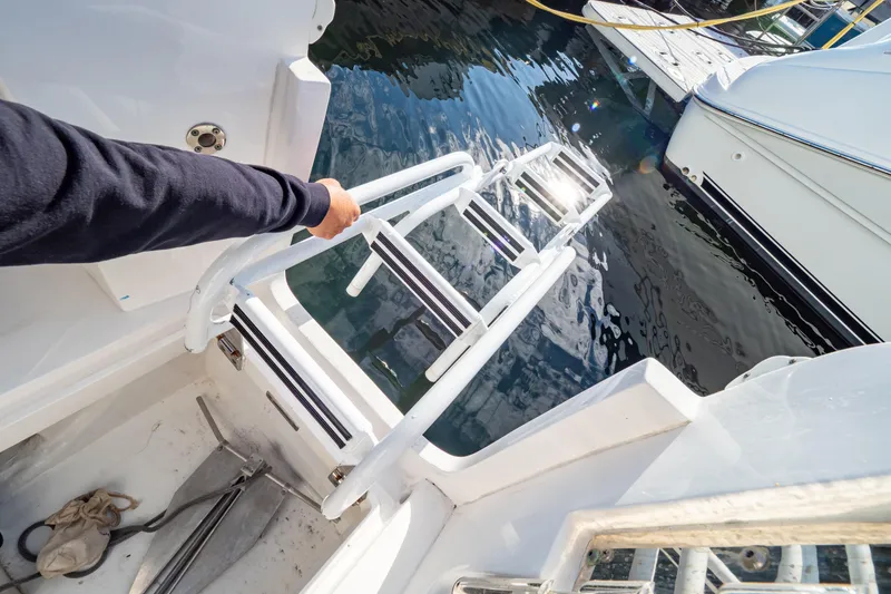 Slide: The Image of Person using ladder on 2018 Intrepid 475 Sport Yacht, docked by water. - 44