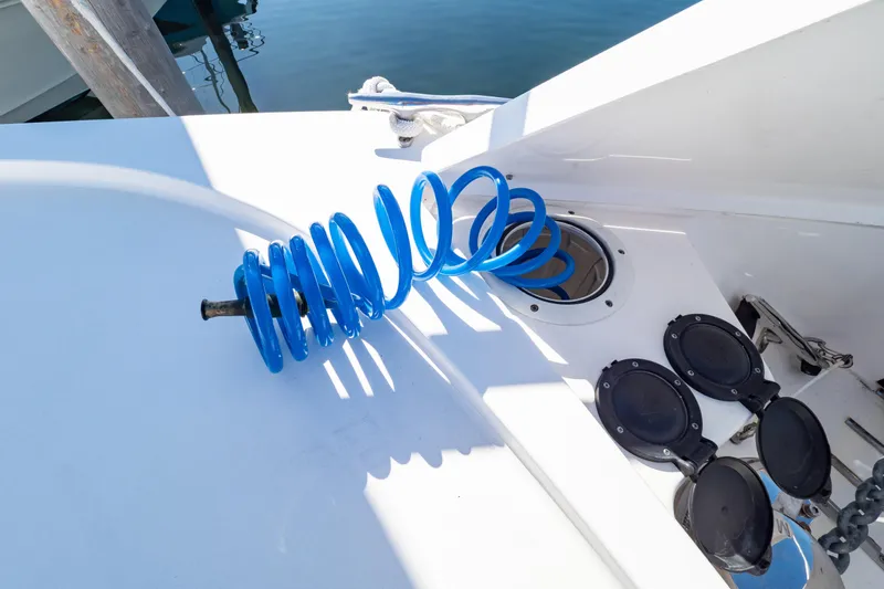Slide: The Image of 2018 Intrepid 475 Sport Yacht deck with blue coiled hose and open hatches. - 80