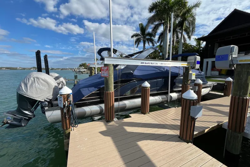 Slide: The Image of 2025 Bennington 30 QX Swingback pontoon boat docked by palm trees. - 2