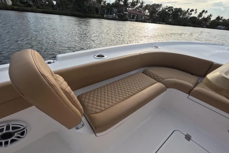 Slide: The Image of Luxurious seating on 2024 Caymas 281 HB boat, featuring tan quilted upholstery by the water. - 10