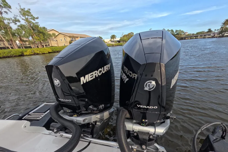 Slide: The Image of Twin Mercury Verado engines on 2024 Caymas 281 HB boat, docked on a scenic waterway. - 20