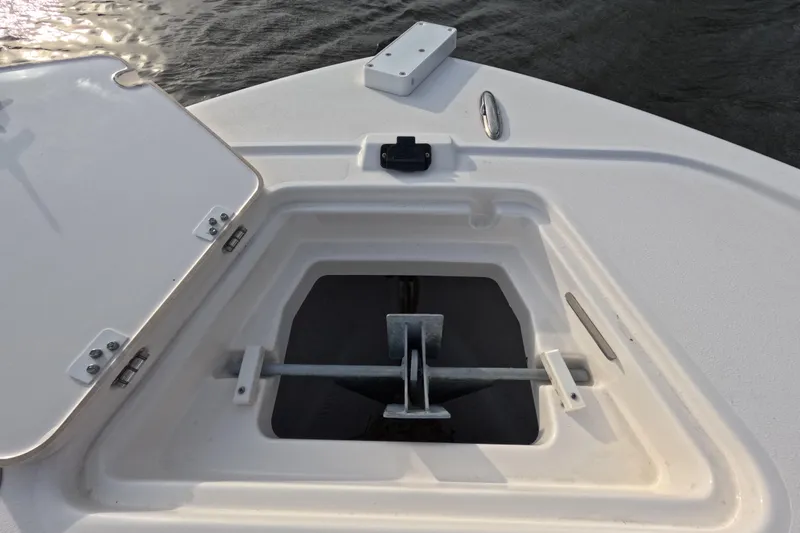 Slide: The Image of 2024 Caymas 281 HB boat anchor compartment with open hatch, on calm water. - 23