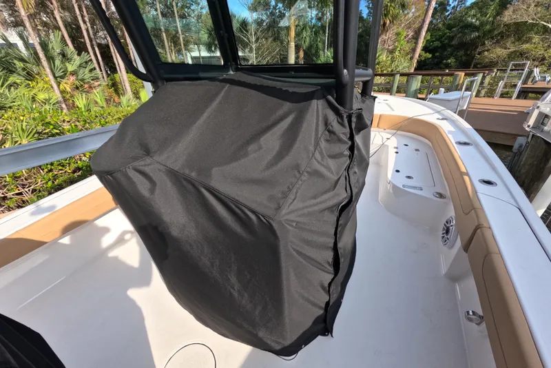 Slide: The Image of 2024 Caymas 281 HB boat interior with covered console, docked near lush greenery. - 29