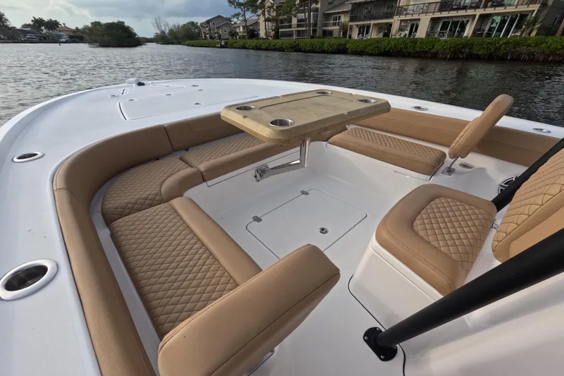Slide: The Image of 2024 Caymas 281 HB boat interior with tan quilted seating and table on a calm waterway. - 8