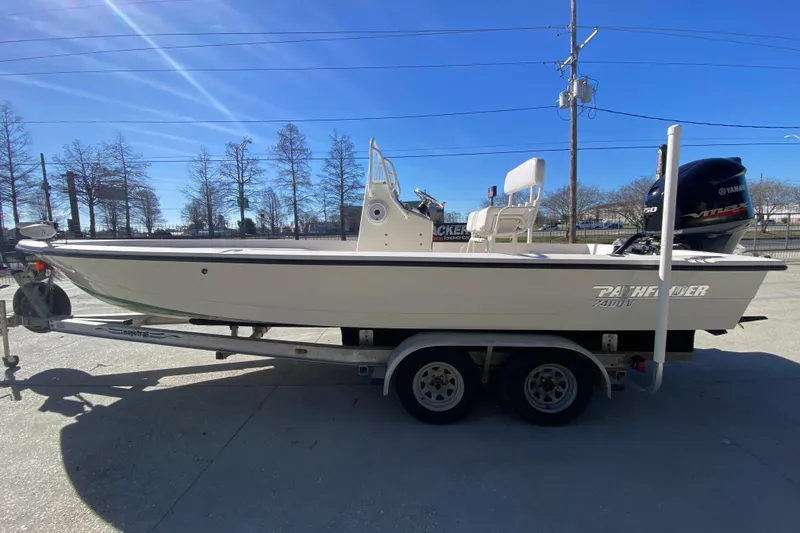 Slide: The Image of 2001 Pathfinder 2400 V boat on trailer, side view, under clear blue sky. - 6