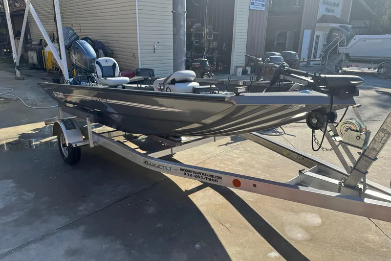 The Image of 2018 Alumacraft Crappie Deluxe boat on trailer, parked outdoors in a marina setting. - 0