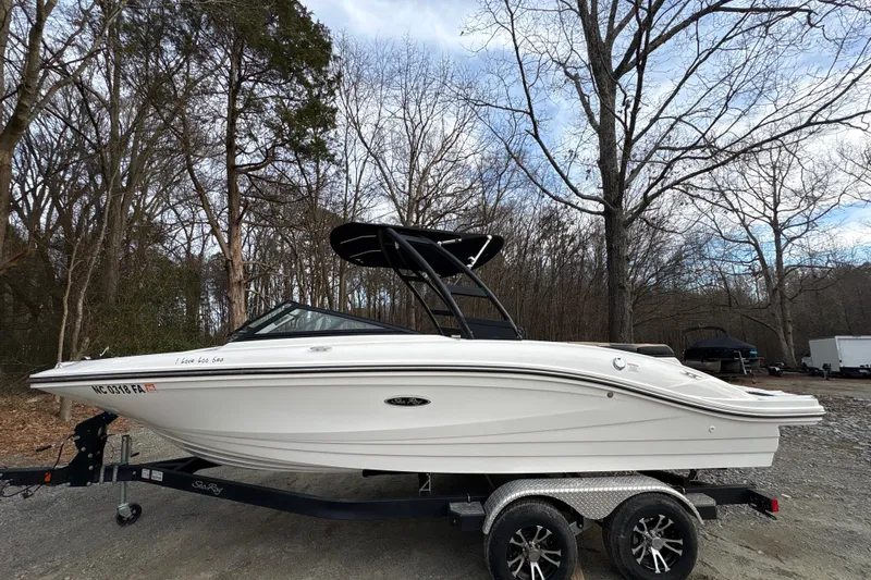 The Image of 2023 Sea Ray SPX 210 boat on trailer, parked in wooded area. - 0