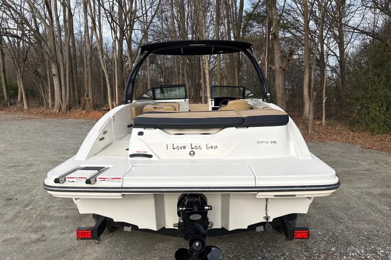 Slide: The Image of 2023 Sea Ray SPX 210 boat, rear view, parked on gravel with trees in background. - 6