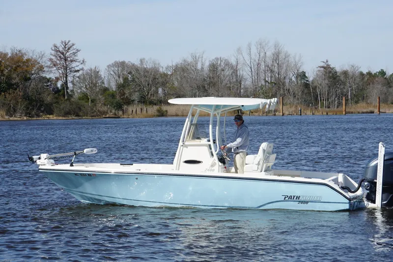The Image of 2023 Pathfinder 2400 TRS boat on a calm river with trees in the background. - 1
