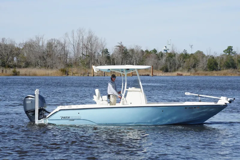 Slide: The Image of 2023 Pathfinder 2400 TRS boat cruising on a calm lake with trees in the background. - 11