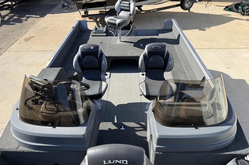 Slide: The Image of 2014 Lund 1875 Impact SS boat interior with seating and console, parked on concrete. - 13