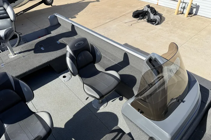 Slide: The Image of 2014 Lund 1875 Impact SS boat interior with seating and windshield, parked on concrete. - 16