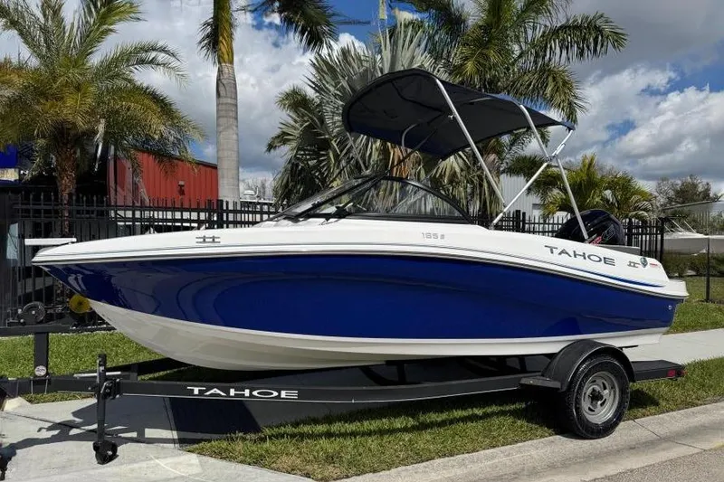 The Image of 2024 Tahoe 185 S boat on trailer, blue and white design, parked near palm trees. - 0