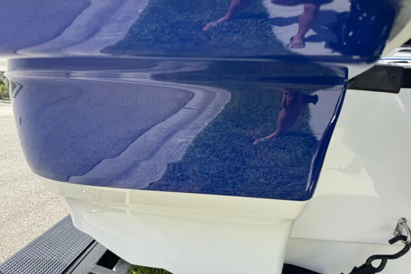 Slide: The Image of 2024 Tahoe 185 S boat hull, glossy blue and white finish, reflecting surroundings. - 12