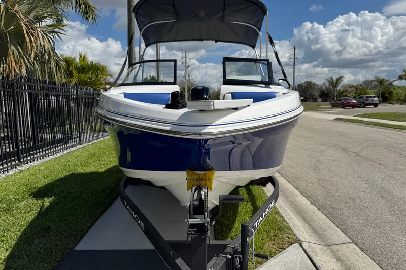 Slide: The Image of 2024 Tahoe 185 S boat on trailer, parked roadside under clear sky. - 18