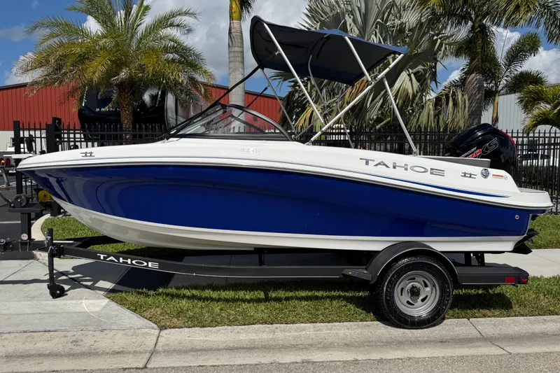 Slide: The Image of 2024 Tahoe 185 S boat with blue hull on trailer, parked near palm trees. - 2