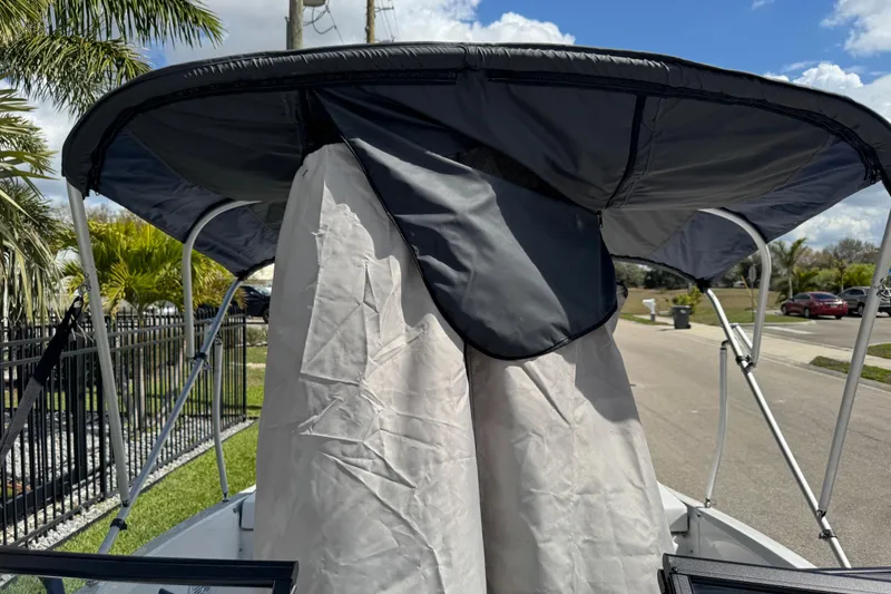 Slide: The Image of 2024 Tahoe 185 S boat with canopy and cover, parked near palm trees. - 80