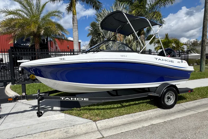 Slide: The Image of 2024 Tahoe 185 S boat on trailer, blue and white design, parked near palm trees. - 89